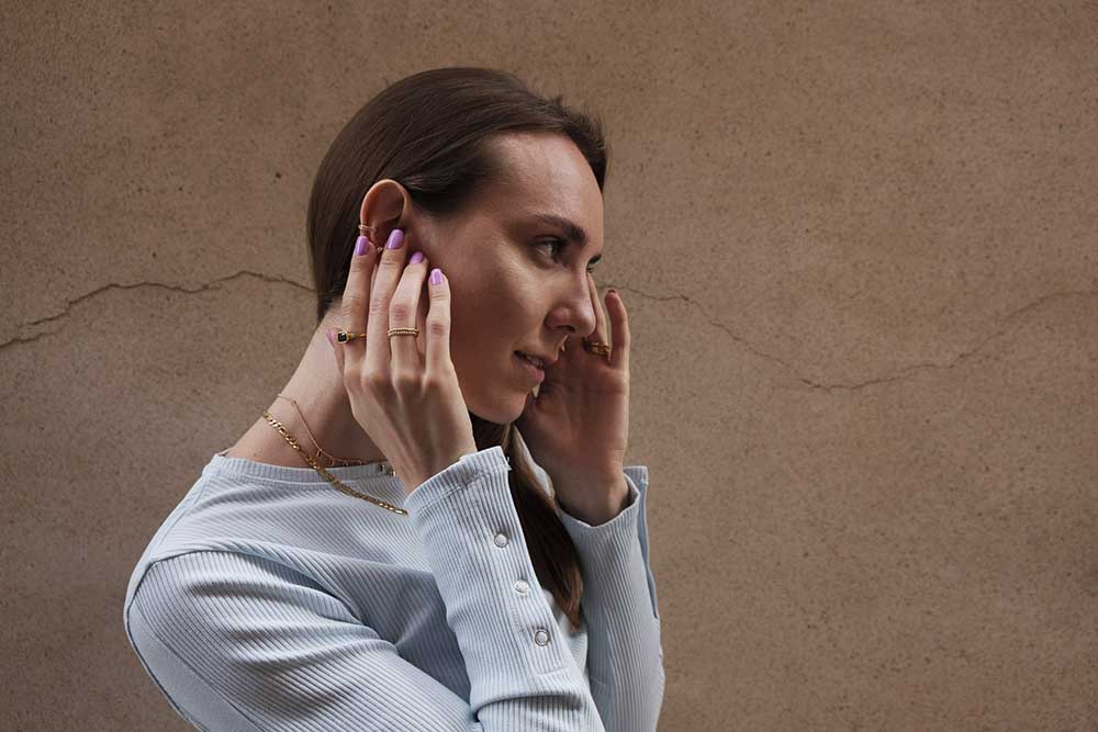 Mujer con varios anillos y collares de plata puestos.